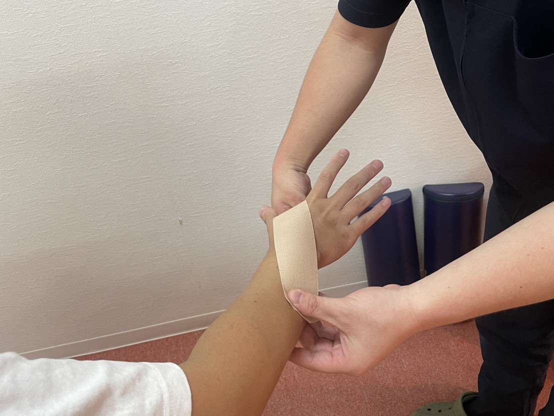 甲賀市のまいれ鍼灸整骨院で腱鞘炎のテーピングをする様子